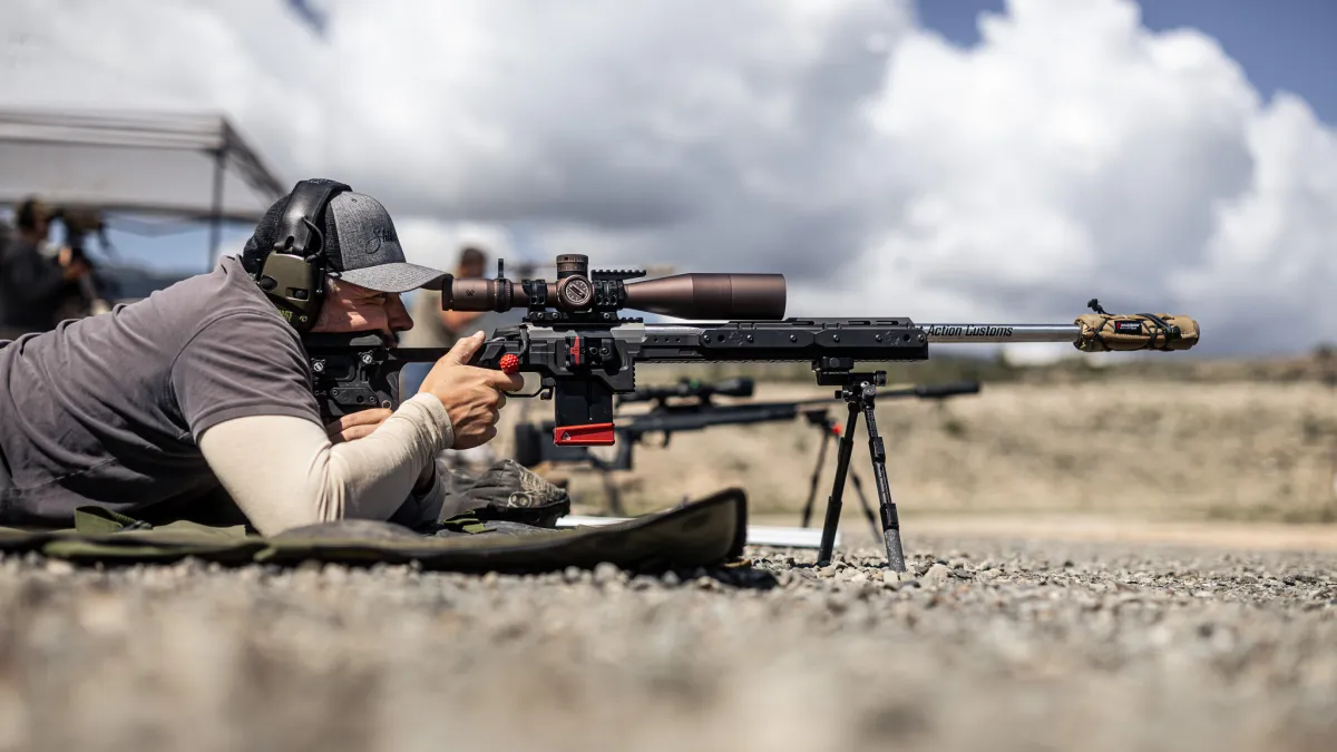 A Cadre shooter prone behind a precision rifle under heavy clouds in Wyoming