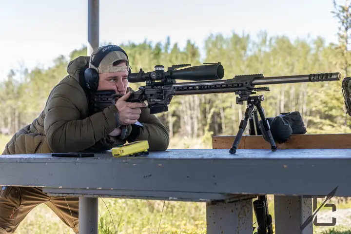 Prone on the bench with bipod, treeline behind