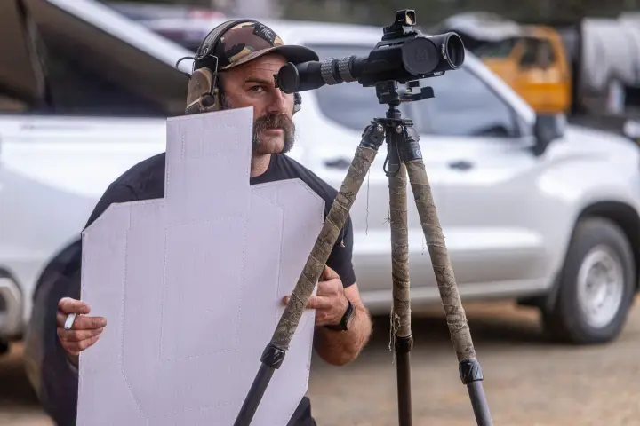 Instructor spotting through a scope, holding a target