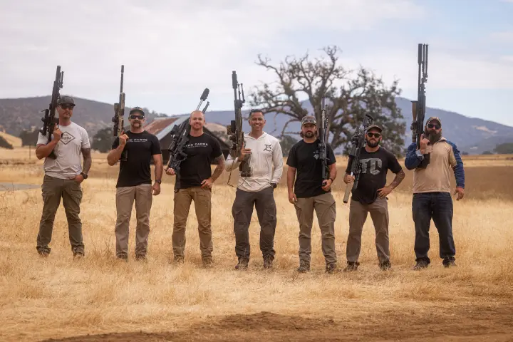 Group photo, rifles raised in the golden field