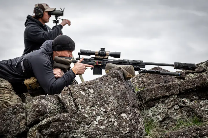 Spotter behind glass, shooter prone on the rocks