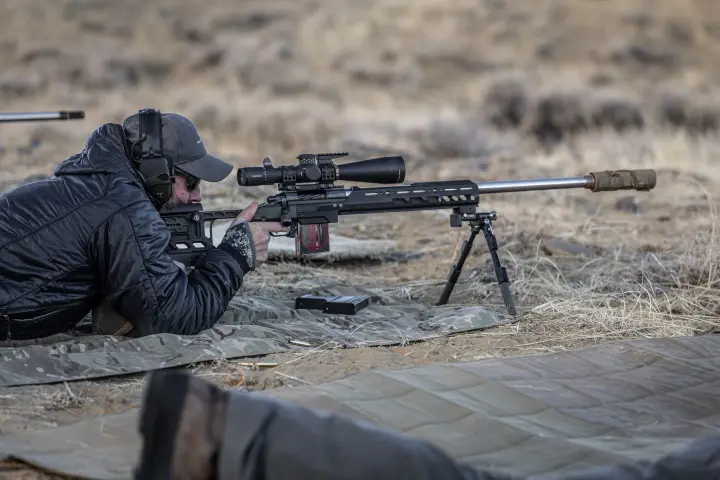 Prone behind a suppressed bolt gun on a mat