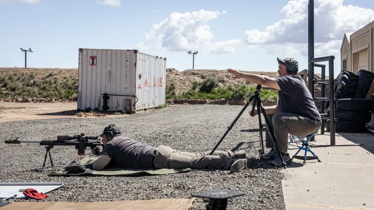 An instructor points out the target to a student shooting prone on a Wyoming range