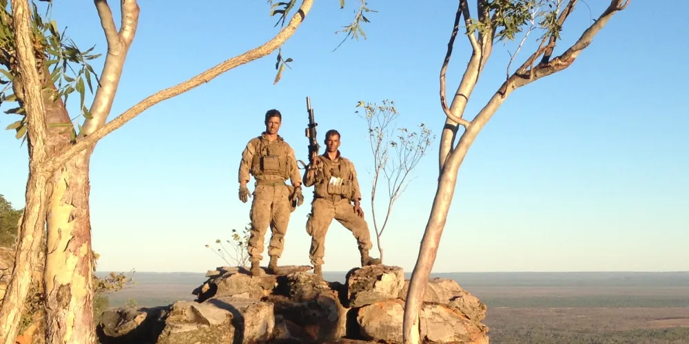 Eric D'Oro and another Marine standing on a rocky overlook during deployment