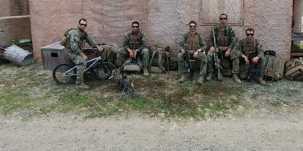 Eric D'Oro seated on a bike with Marines from his sniper platoon