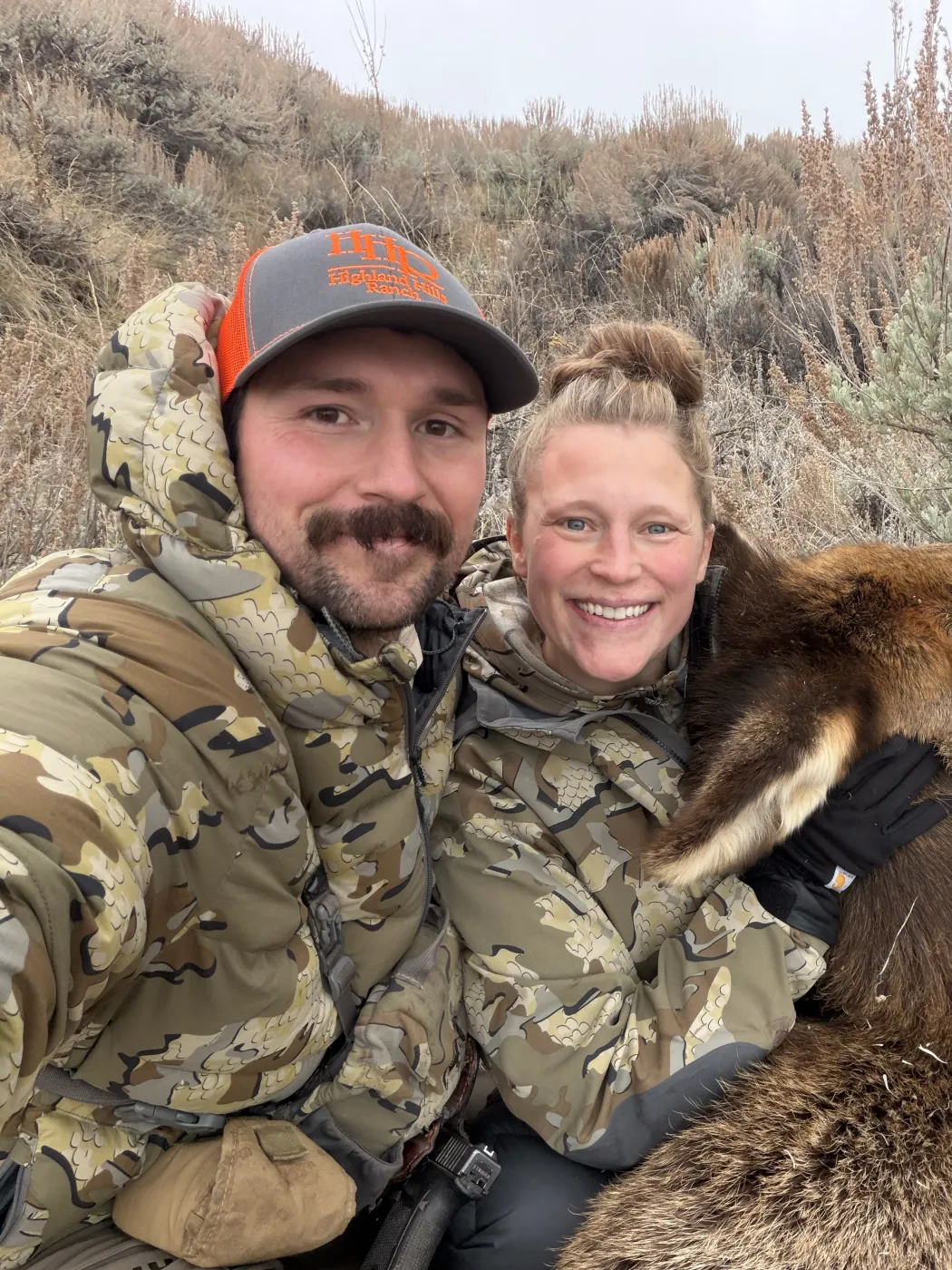 Ian Miner and his wife Ashley smiling beside a cow elk she harvested on a hunt