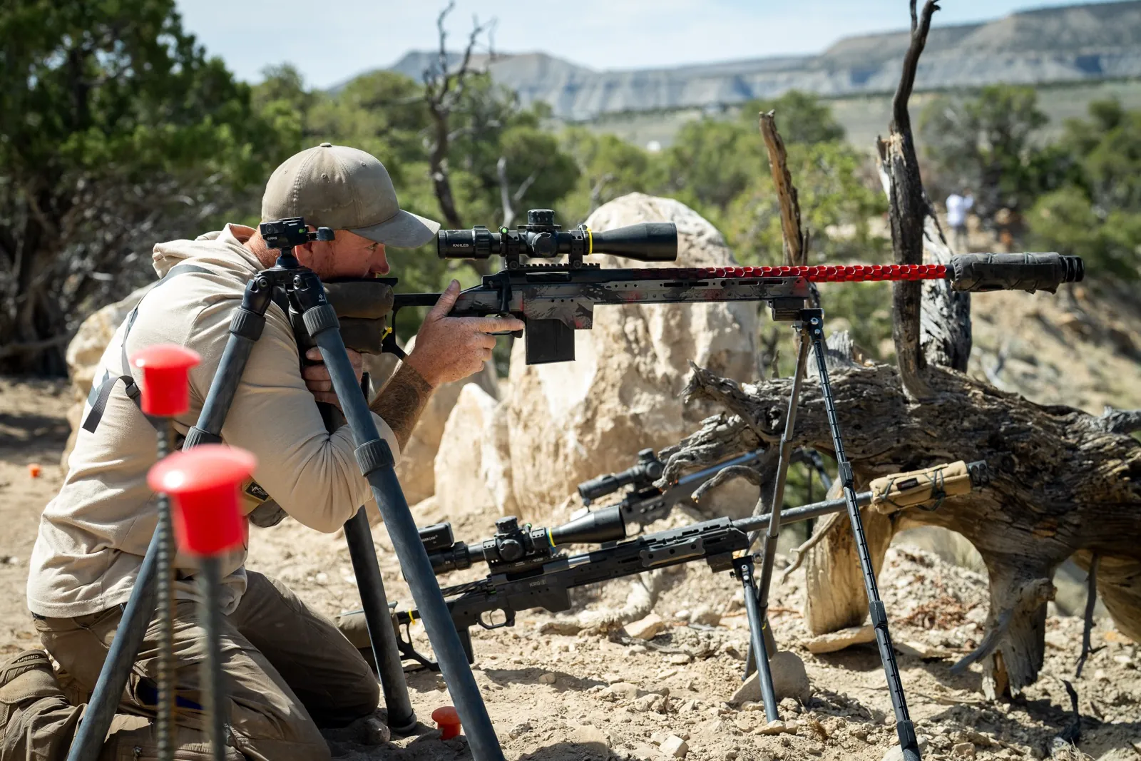 Jon Bumpus behind his NRL Hunter rifle off a tripod, high desert country behind him