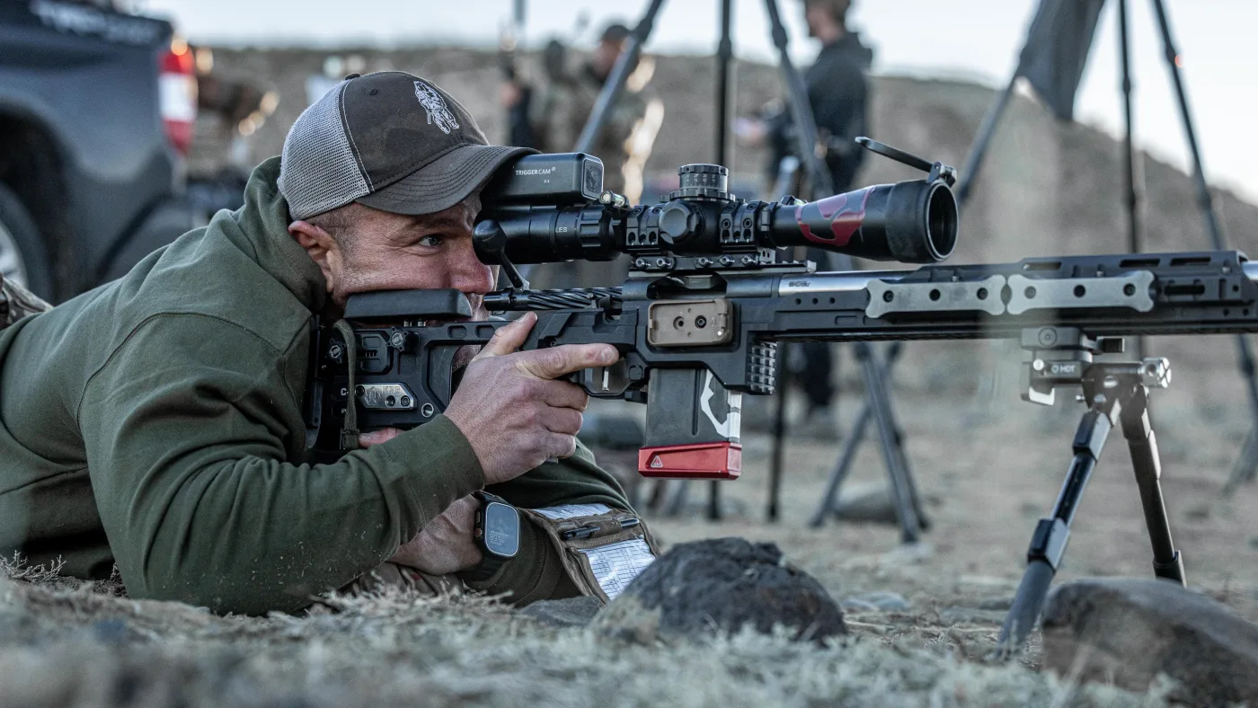 Matt Solowynsky prone behind a chassis rifle, magazine inserted, dialed in on the scope