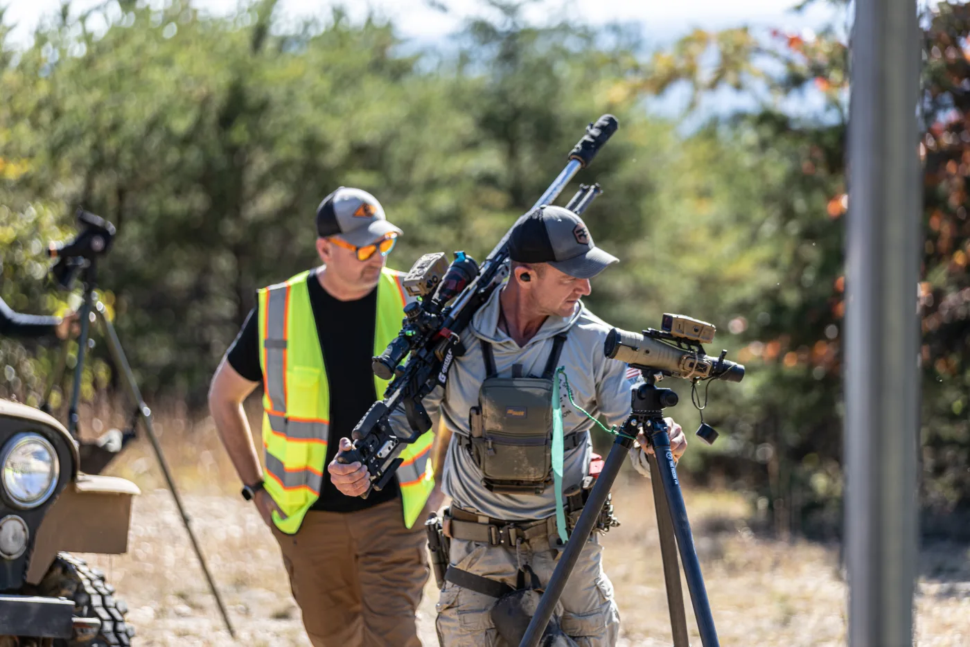 Matt Solowynsky carrying his rifle and tripod to the next stage, a range officer alongside