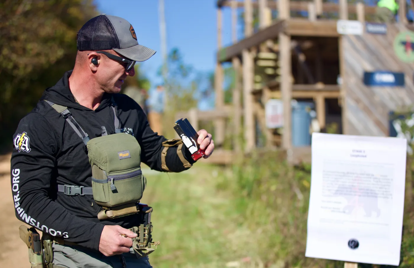 Matt Solowynsky loading a magazine while studying a stage brief at the Jim Land Sniper Cup