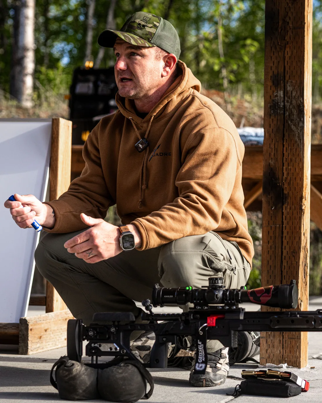 Matt Solowynsky kneeling beside a rifle, talking a class through a point