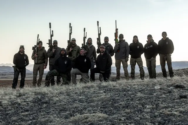 The 2024 Invite crew holding rifles overhead at sunset