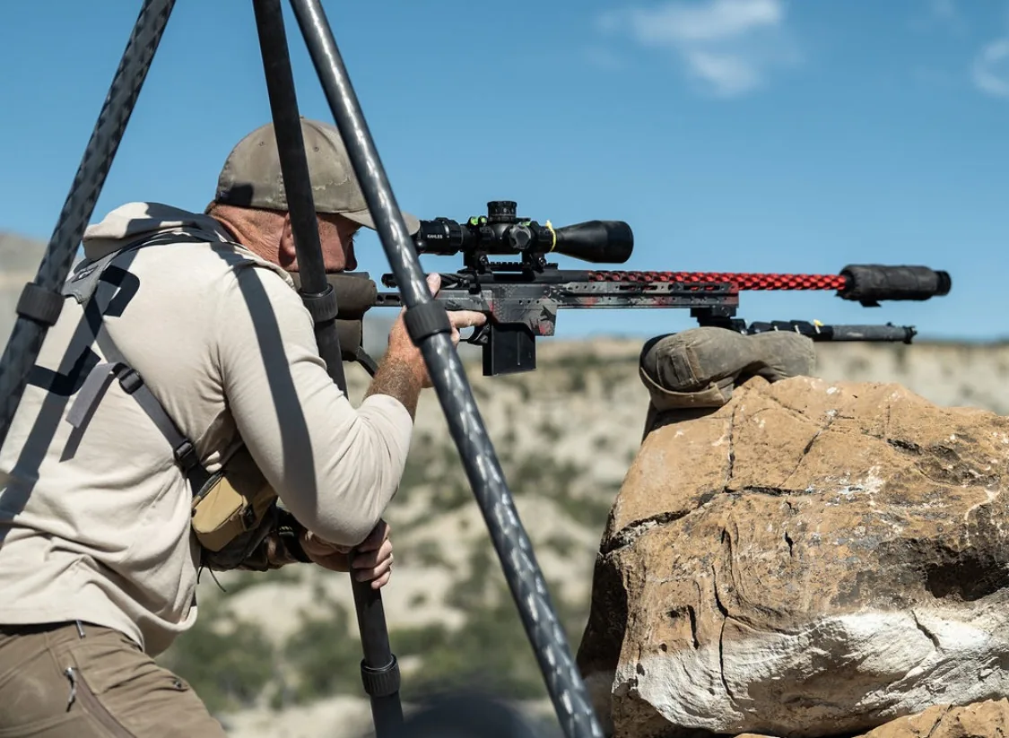 Instructor shooting from a front support bag on a natural rock rest.